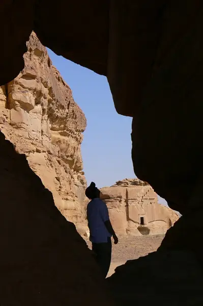 A man looking up at a rock formation