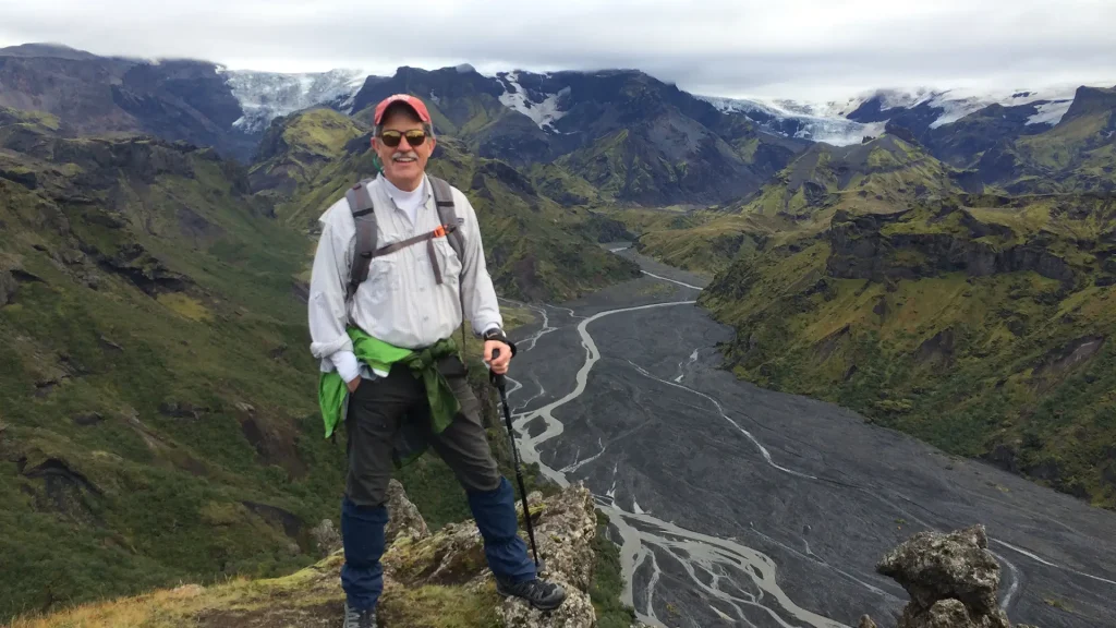 A man posing for a photo in front of mountains and valleys