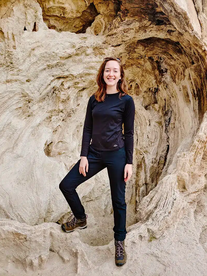 Sara Shields stands against the backdrop of geologic rocks.